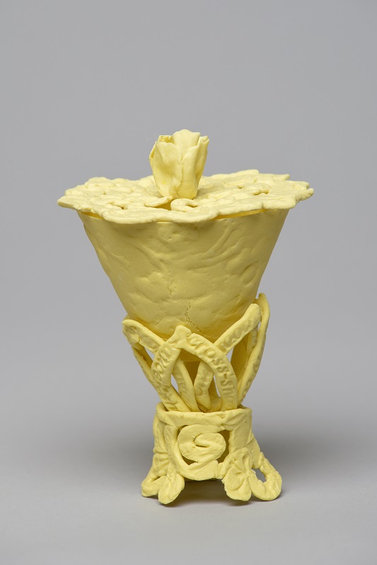 Delicate, light yellow ceramic vessel with a lid and decorative elements on the base