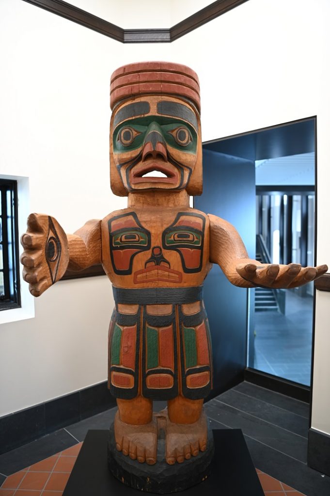 Cedar wood sculpture of figure with painted black, green and red regalia
